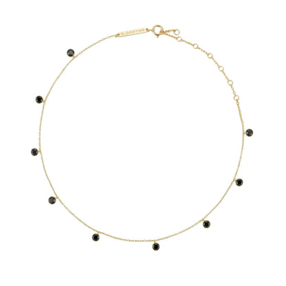 A delicate gold chain necklace with small, evenly spaced round black gemstone beads, displayed on a clean white background.