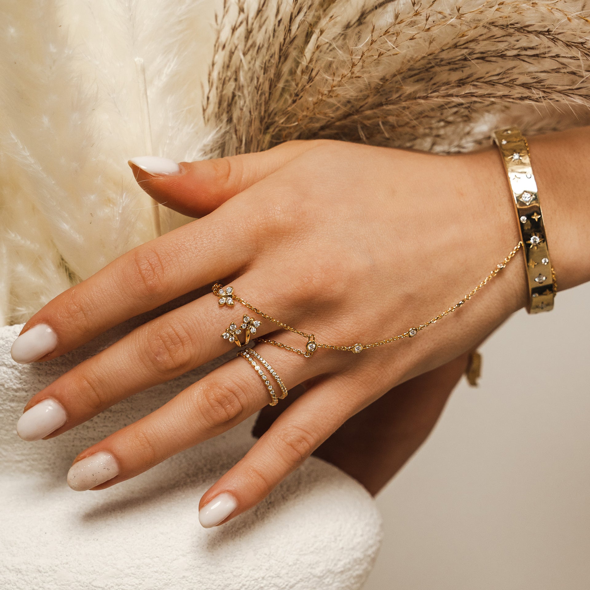 BLOOMTINE | Goddess Hand Stack | Gold Jewellery. Hand wearing gold rings, gold hand chain and Gold Star Bangle with a neutral background