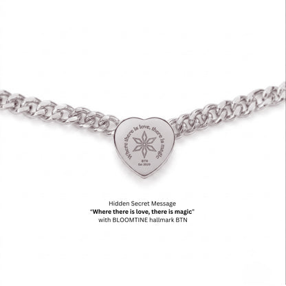 A silver heart-shaped pendant charm on a silver curb chain, featuring the engraved message 'Where there is love, there is magic' and 'BLOOMTINE' with a starburst symbol. Text below reads 'Hidden Secret Message' and 'with BLOOMTINE hallmark BTN'.