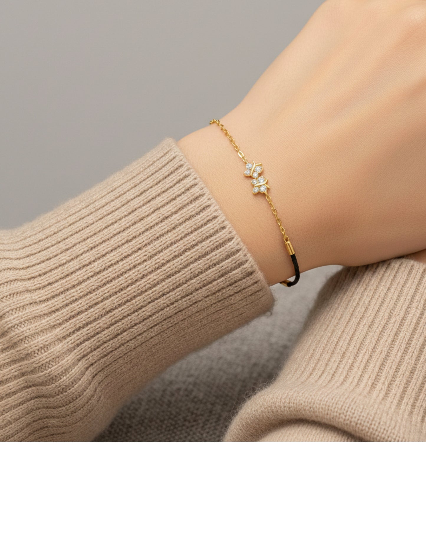 Gold bracelet with a star design on a wrist wearing a beige sweater.