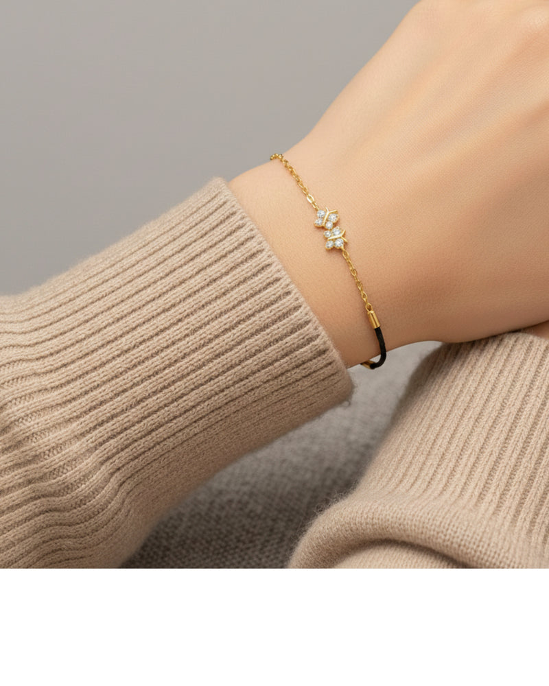 Gold bracelet with a star design on a wrist wearing a beige sweater.