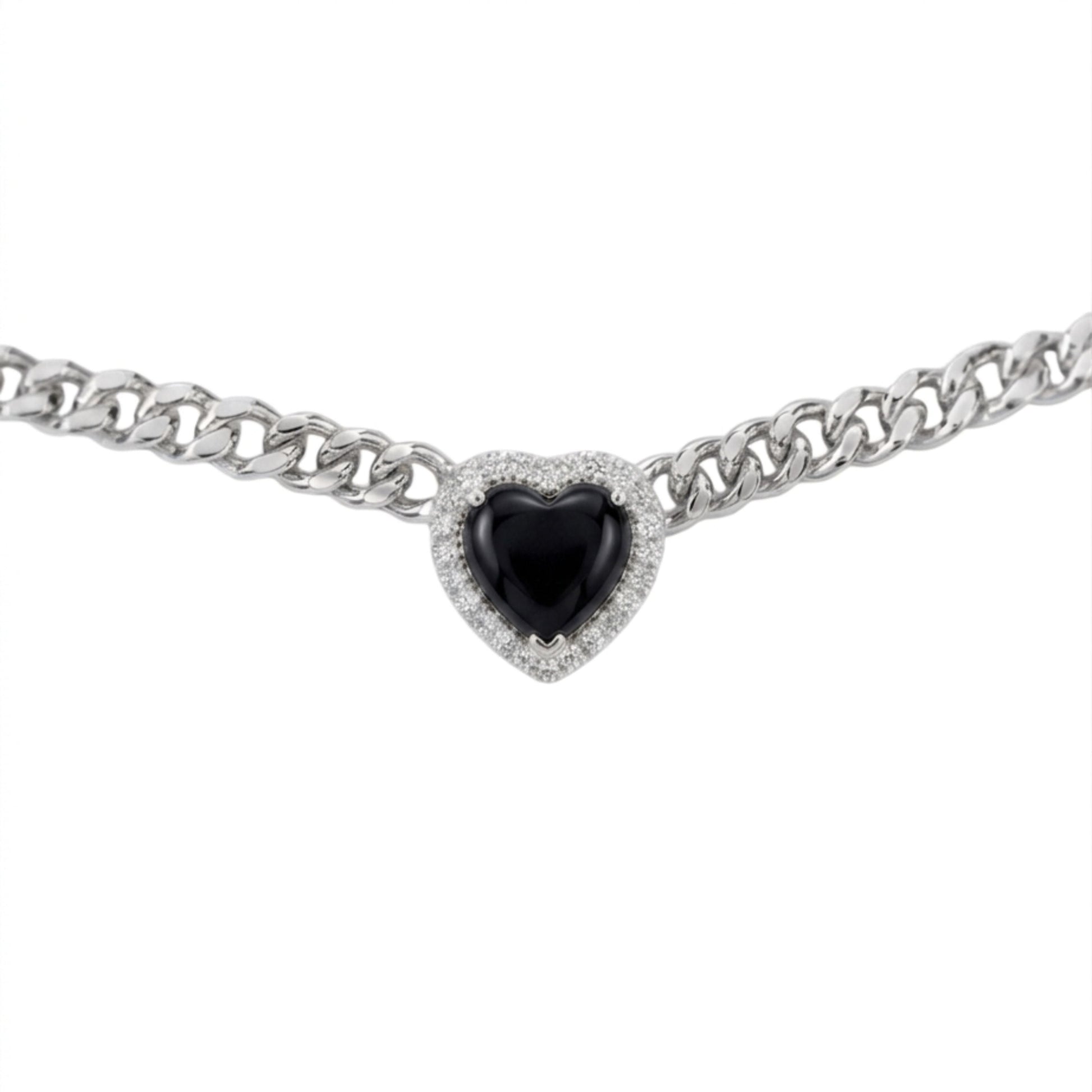 A silver-toned curb chain bracelet featuring a heart-shaped black gemstone surrounded by a halo of small clear stones, set against a plain white background.
