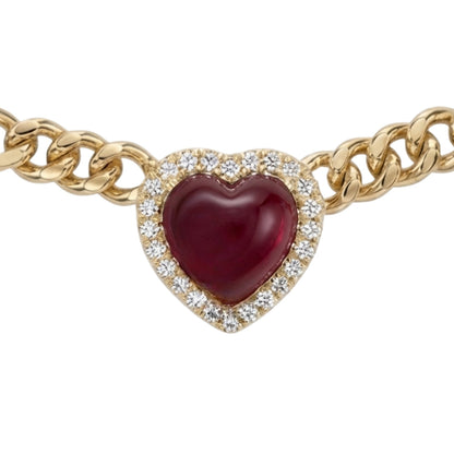 A gold heart-shaped chain bracelet featuring a central heart pendant with a deep red cabochon gemstone surrounded by a halo of small clear stones, set against a plain white background.