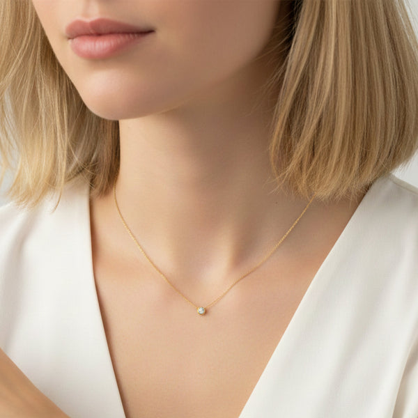 Close-up of a person wearing a gold necklace with a small pendant.