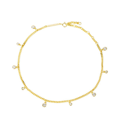 A close-up shot of the Illuminess™ Apah Water Goddess Anklet in premium gold vermeil, modeled on an olive-toned ankle. The dainty silver chain features shimmering lab-diamond droplets that catch the light, creating a liquid-sparkle effect