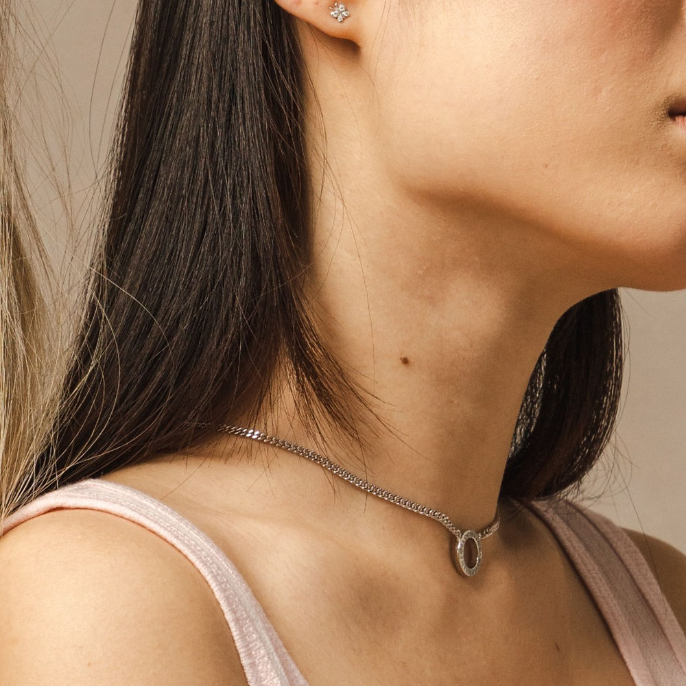 A side-view lifestyle-shot of a model wearing the Mini-Halo-Wings-sterling-silver-diamond-angel-choker inside the Bloomtine-Boutique in Paddington. The-image captures the-delicate-wing-design and shimmering-diamond-accents of the-choker, set-against a backdrop of the-full Mini-Halo-Wings-jewellery-range. This-in-store-photograph highlights the-premium-925-sterling-silver-craftsmanship and elegant-fit, showcasing the-exclusive-collection available at our London-jewellery-boutique for customers seeking-angeli