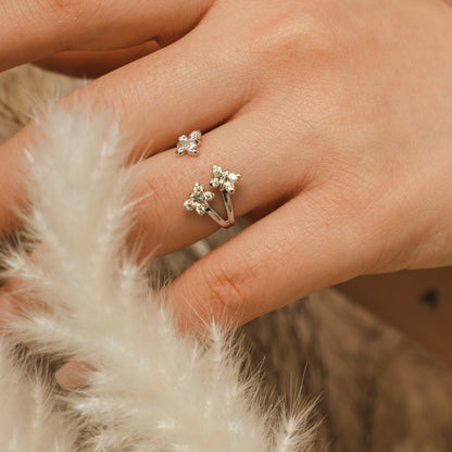 Close-up of a hand wearing two silver rings with star designs on a soft, beige background. Close-up-detail of the Bloomtine-Enchanting-Flutterfly-ring. The-macro-photography showcases the-four-scintillating-moissanites and their-majestic-light-refraction. This-image emphasizes the-handmade-artistry and precision-setting of the-gemstones in solid-925-sterling-silver, highlighting the-durability and premium-quality of this-best-selling-spiritual-symbolism-jewellery