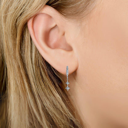 Illuminess™ Mini Sterling Silver Shooting Star Huggies image 2. Bloomtine-Mini-Shooting-Star-Huggies. A professional-hero-shot of 925-sterling-silver-celestial-hoop-earrings featuring a-trail of four-sparkling-moissanite-shooting-stars. Displayed-on-a-clean-white-background, these-huggies highlight the-brilliant-white-rhodium-finish and sustainable-gemstone-accents, representing-abundance and divine-guidance